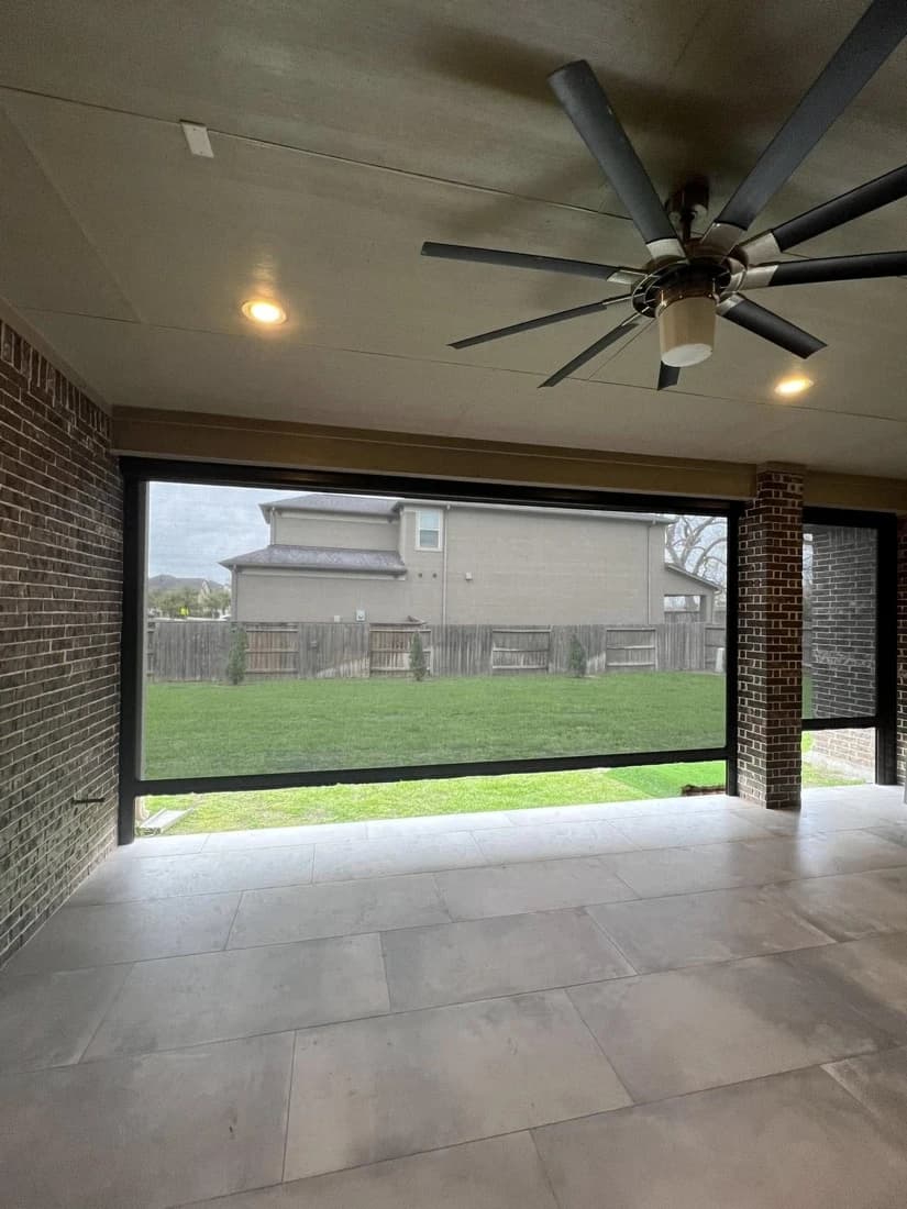 Outdoor living room with a retractable motorized screen lowered for privacy