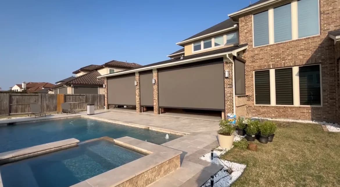 Motorized patio screens lowered under a cedar pergola at a Houston home